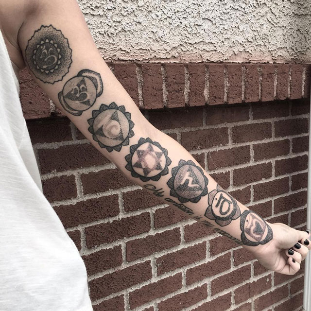 arm decorated with tattoos of hindu symbols